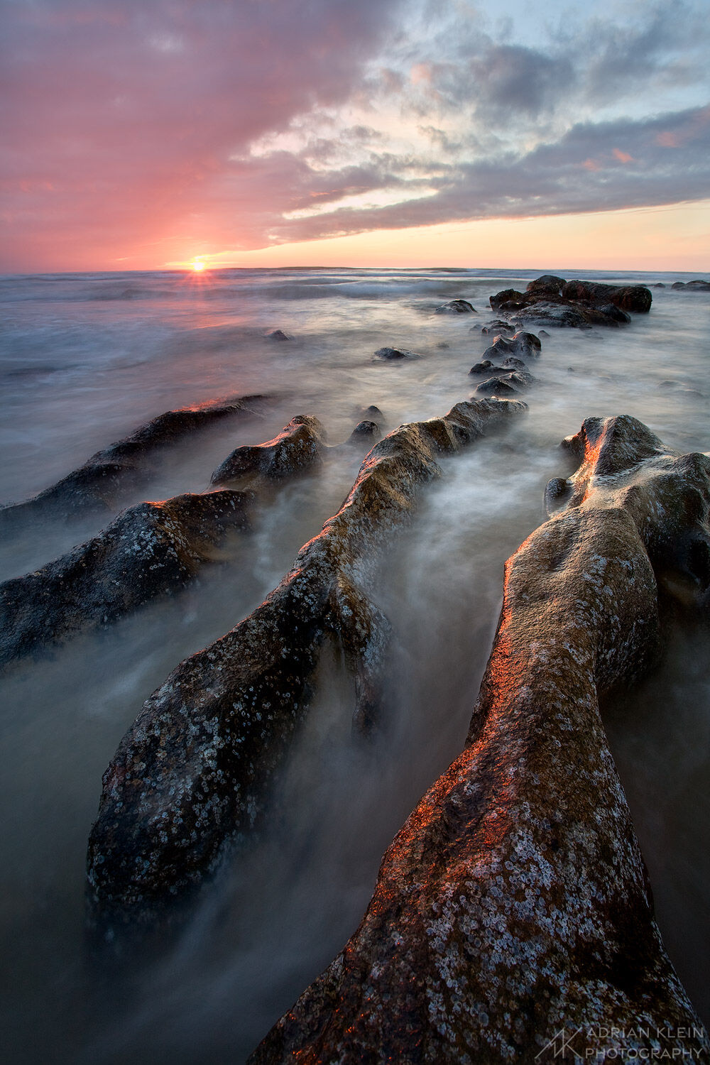 Rock ribs jut out along the Oregon coast at sunset.