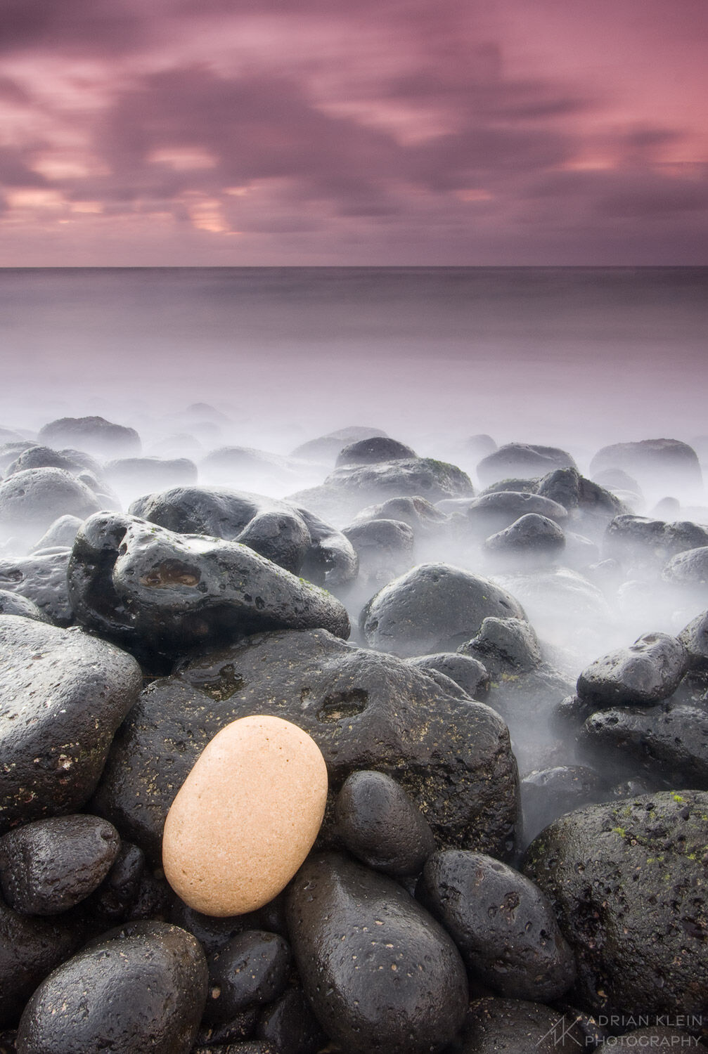 A lone white rock among a black rocky shore in Kauai, Hawaii taken at sunrise on the South Shore near Poipu as long exposure...