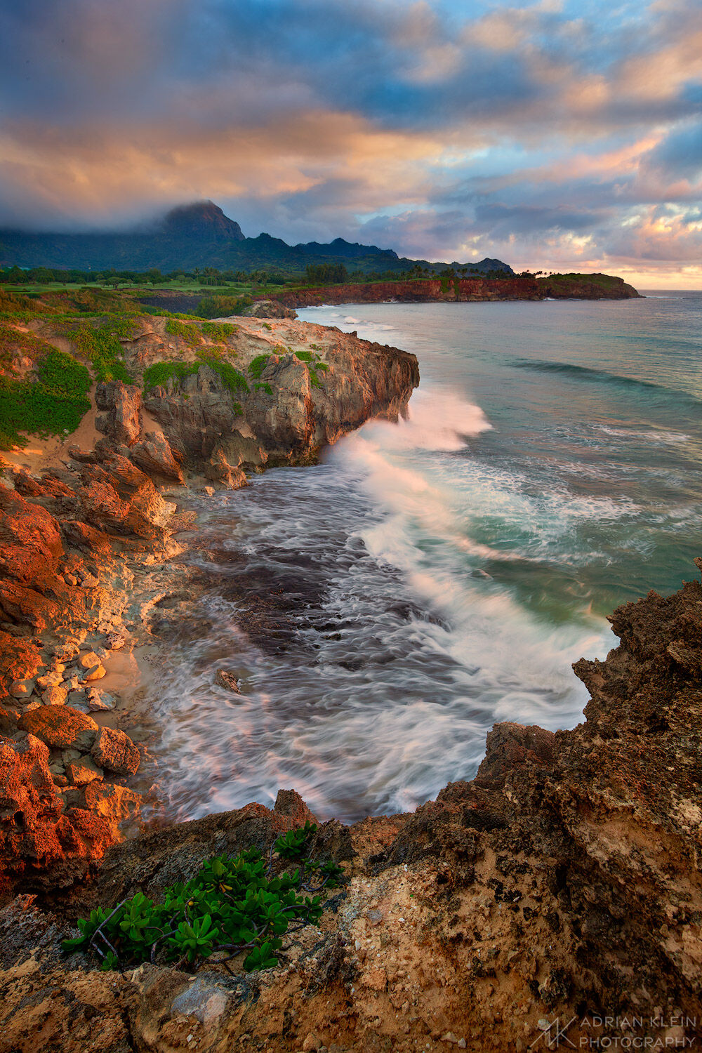 Standing on a cliff edge on the south shore of Kauai the sunrise glows along the rocks and breaking sky. A short sandy hike took...