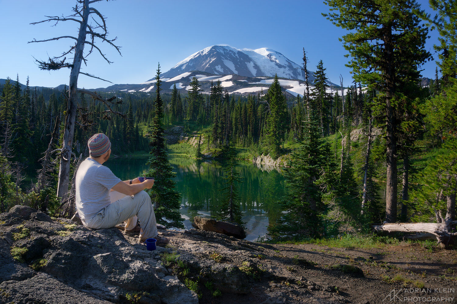 Self portrait along side a lake watching the sunrise onto Mount Adams while eating oatmeal and drinking coffee. Backpacking in...
