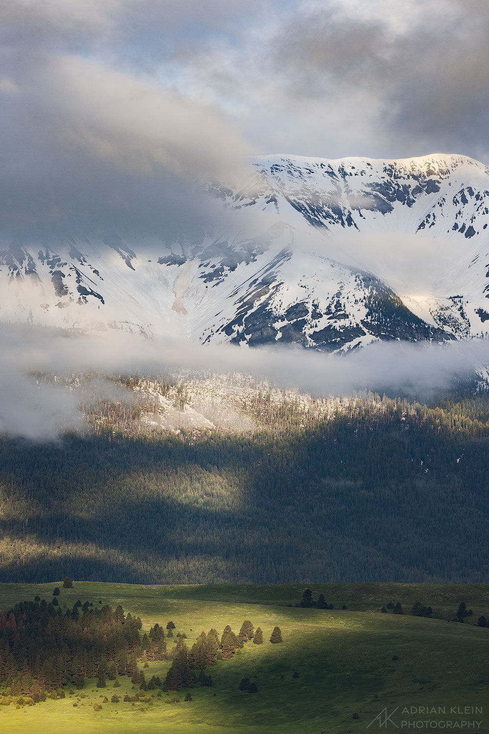 Clouds part and the light shines in on the Wallowa Mountains in Eastern Oregon during spring season shortly after sunrise.